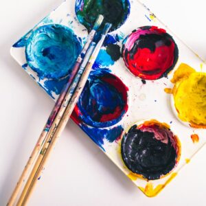 godê com diversas cores de tinta e pincéis