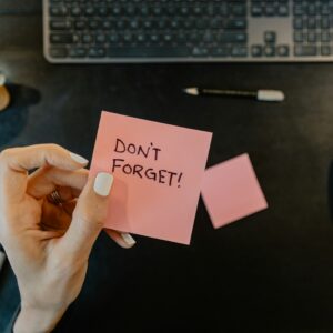 pessoa segurando um post it onde está escrito não se esqueça