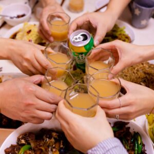 um grupo de pessoas brindando com bebidas em uma mesa de jantar