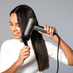 a woman blow drying her hair with a hair dryer
