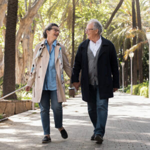 casal idoso caminhando em um parque de mãos dadas
