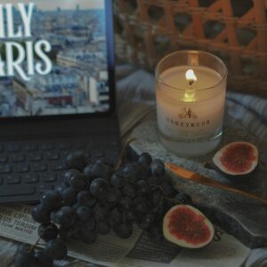 A cozy still life featuring a candle, grapes, figs, and a tablet screen with Paris imagery.