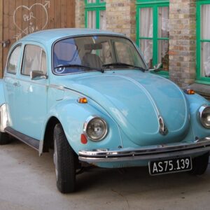 parked teal Volkswagen Beetle coupe beside wall