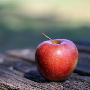 a red apple sitting on top of a wooden table