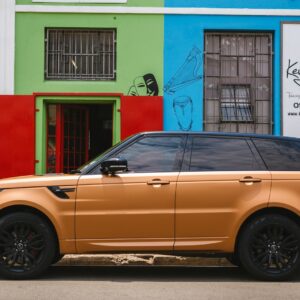 brown suv parked beside green and pink concrete building during daytime