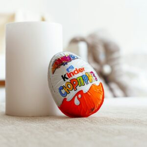 a white cup sitting next to an orange and white egg