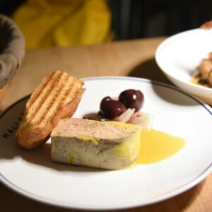 Foie gras with toast and olives on a plate.