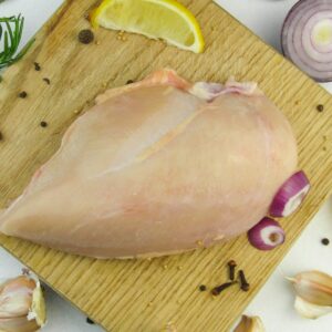 a raw chicken on a cutting board with garlic, lemon, and garlic