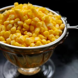 Close-up of fresh yellow corn kernels in a stainless steel bowl, perfect for food-related content.