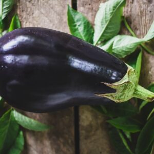 an eggplant on a wooden surface with leaves