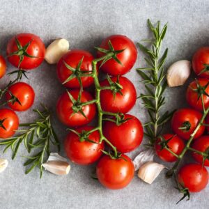 cachos de tomate cereja vistos de cima com dentes de alho e alecrim