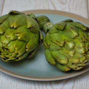 Two fresh artichokes on a blue plate, perfect for healthy cooking and food photography.