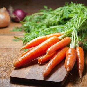 A bunch of fresh organic carrots on a wooden board, emphasizing healthy eating.