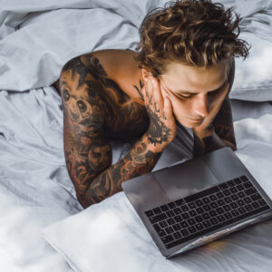 homem deitado na cama olhando a tela do computador