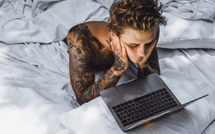 homem deitado na cama olhando a tela do computador