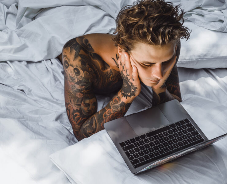 homem deitado na cama olhando a tela do computador