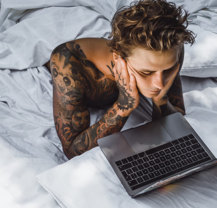 homem deitado na cama olhando a tela do computador