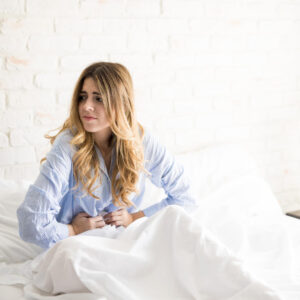 mulher com ar desanimado sentada na cama