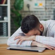 homem debruçado sobre uma mesa, cansaço, estudar,