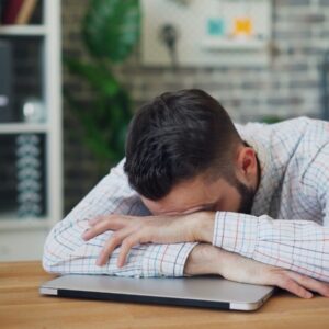 homem debruçado sobre uma mesa, cansaço, estudar,
