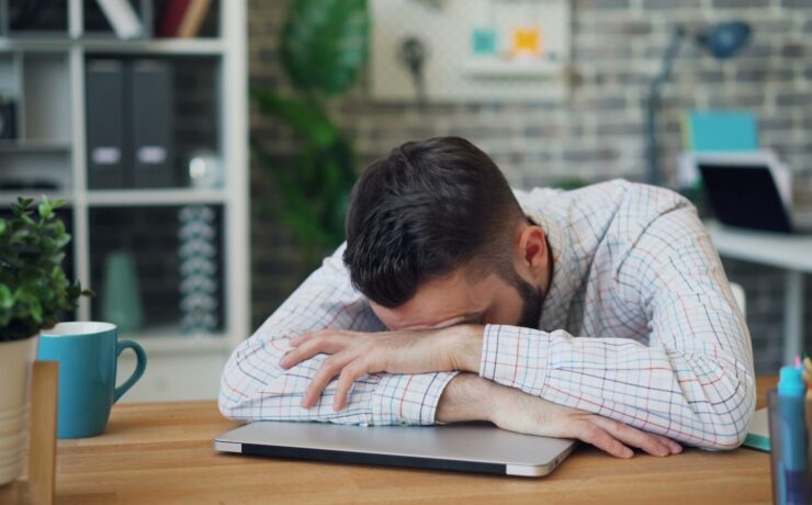 homem debruçado sobre uma mesa, cansaço, estudar,