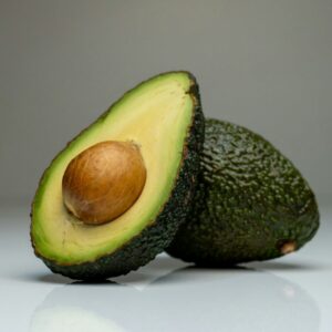 um abacate cortado ao meio sobre uma superfície branca