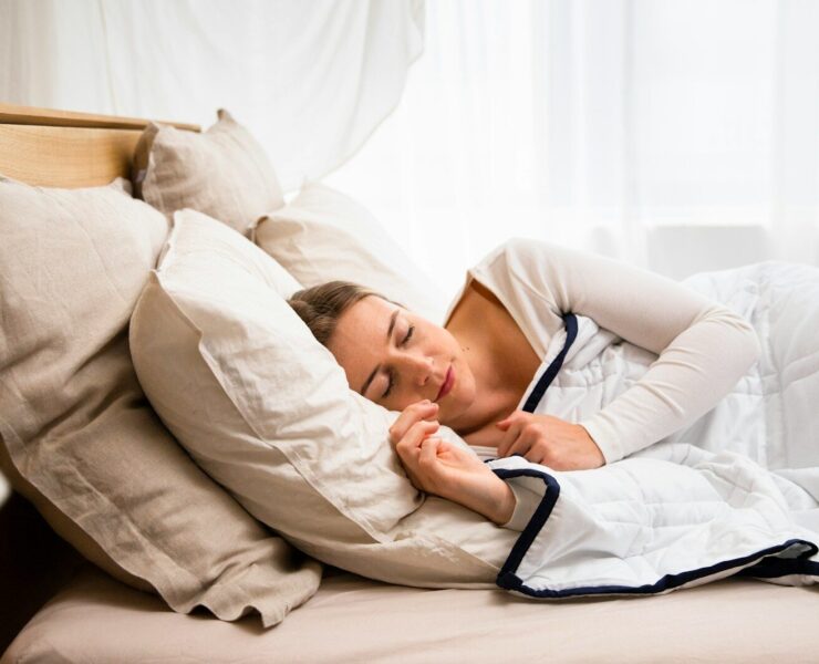 uma mulher dormindo em uma cama com um edredom branco