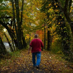 man in red hoodie walking on forest during daytime